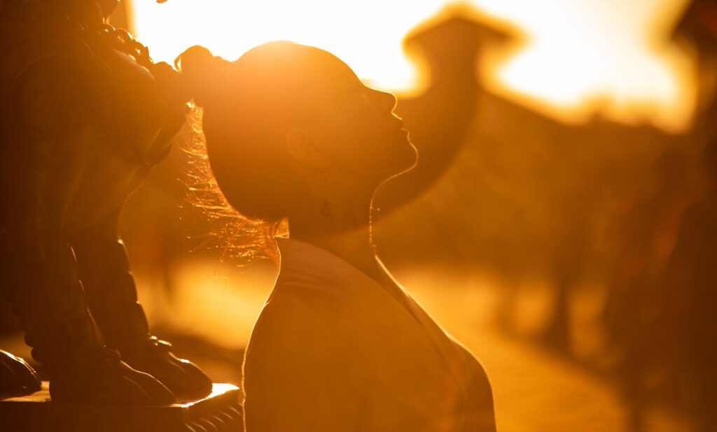 Home Golden silhouette of a woman against a bright sunset, capturing serene beauty.